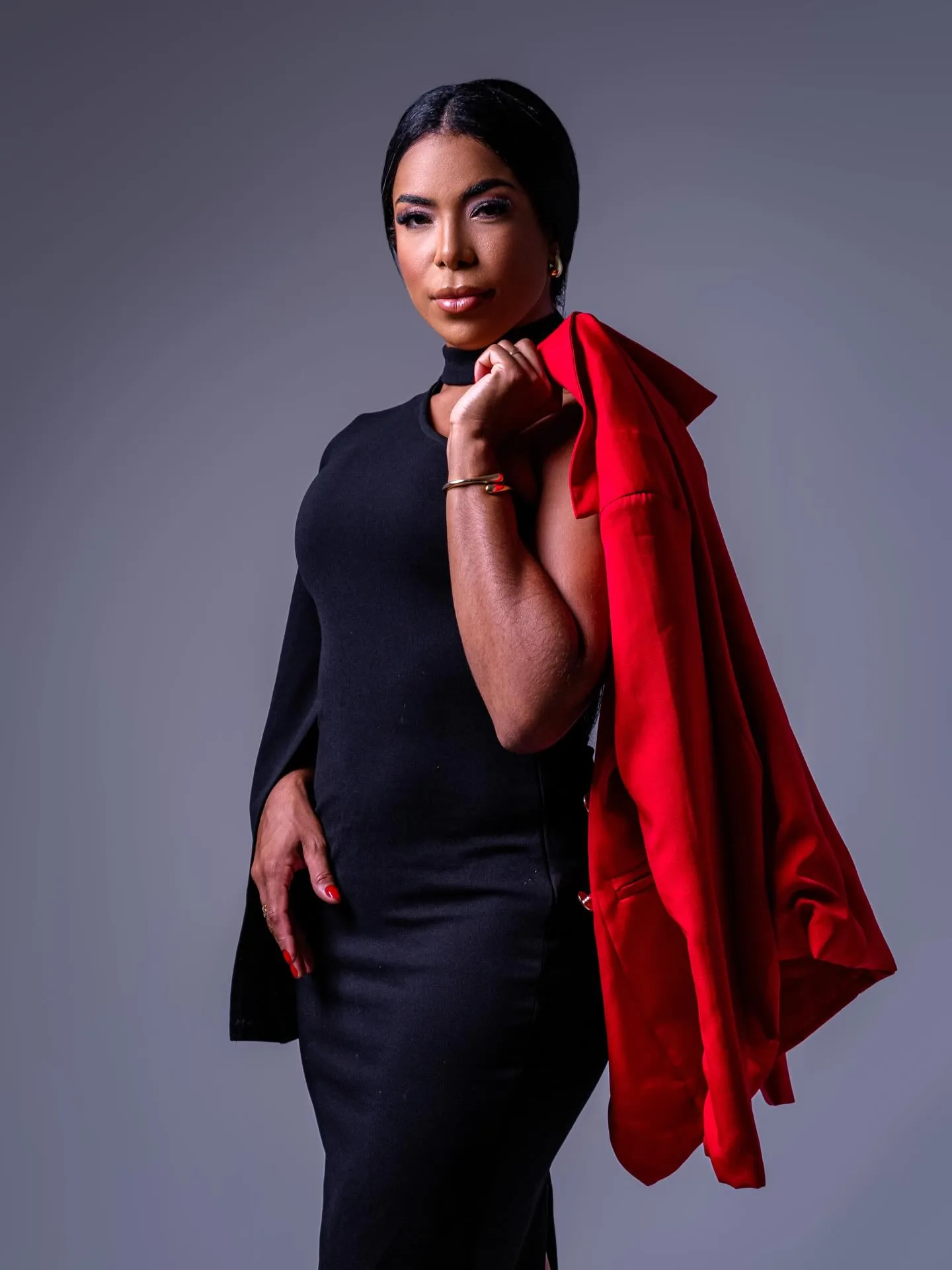 Dra. Janaína Andrade, advogada criminalista, de vestido preto, com um blazer vermelho sobre o ombro, olhando firme para a câmera.
